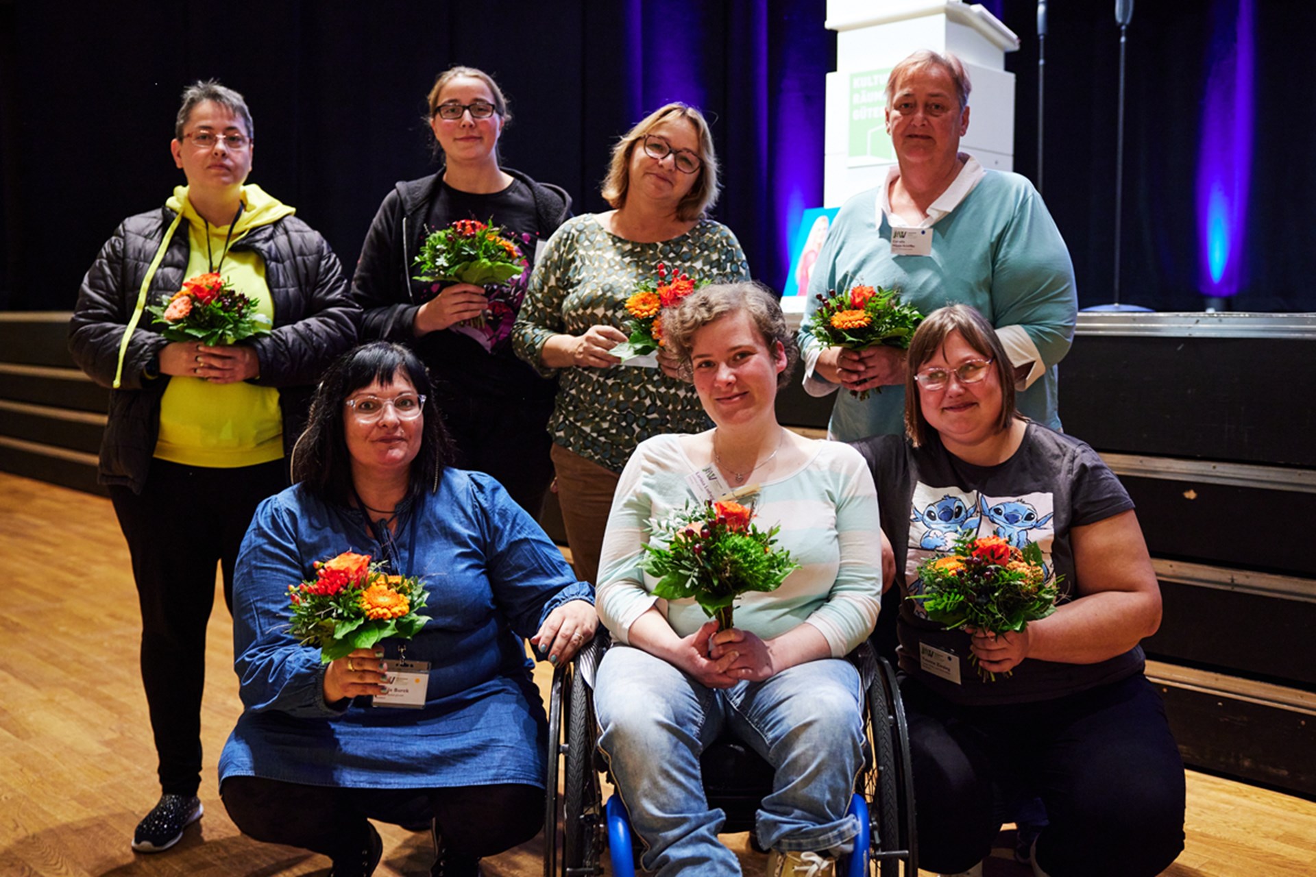 Gruppenfoto der Gründungsfrauen einer geplanten LAG für Frauenbeauftragte in NRW, die auf einer Bühne jeweils einen Blumenstrauß in die Händen tragen