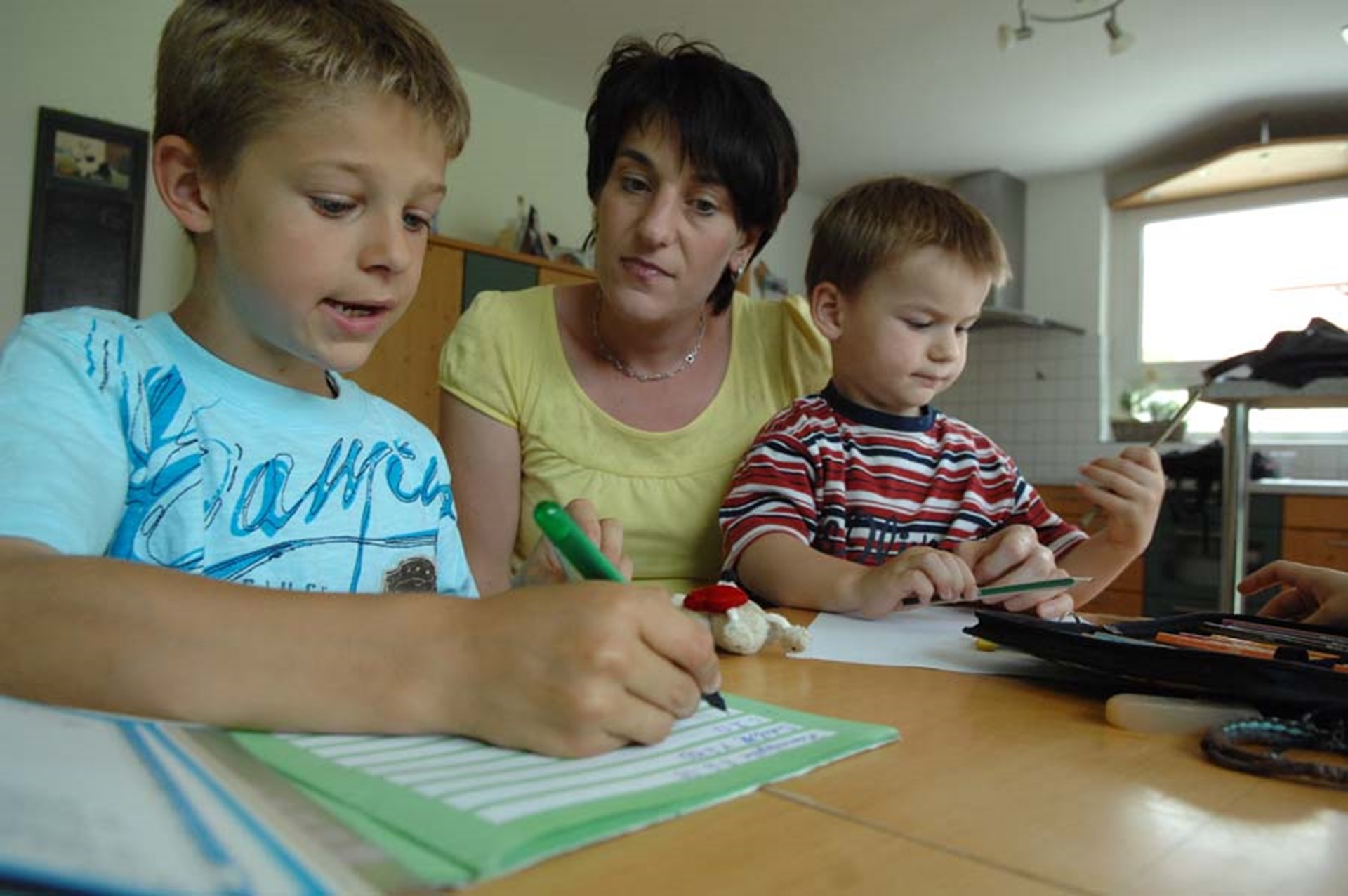 Mutter mit Kindern bei den Hausaufgaben 