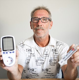 Ein Mann, der einen programmierbarem Strom-Stecker und ein Thermometer hochhält