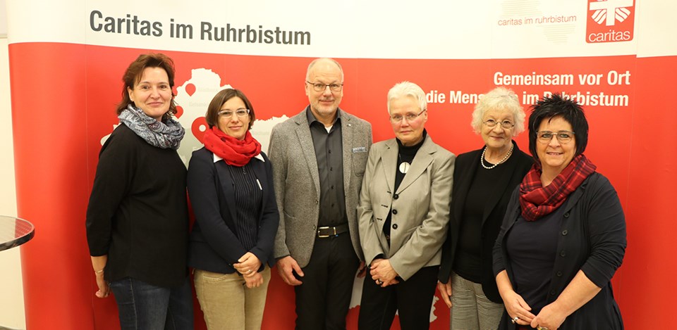 Die Referent/innen einer Fachtagung der Caritas in NRW zum Pflegeberufegesetz in Essen, die vor einem Faltdisplay der Caritas im Ruhrbistum stehen