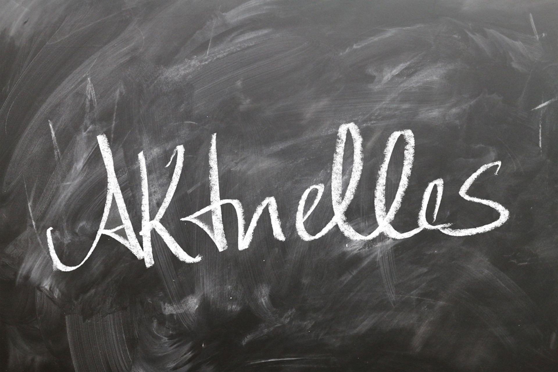 Eine verschmierte Kreidetafel, auf der das Wort 'Aktuelles' steht