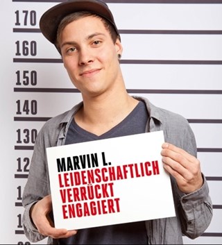 Plakatmotiv zur Kampagne 'CARITÄTER - Täter mit Profil' mit einem lächelnden, jungen Mann vor einer Größen-Skala mit einem Schild. Auf dem Schild steht: Marvin L. - leidenschaftlich - verrückt - engagiert