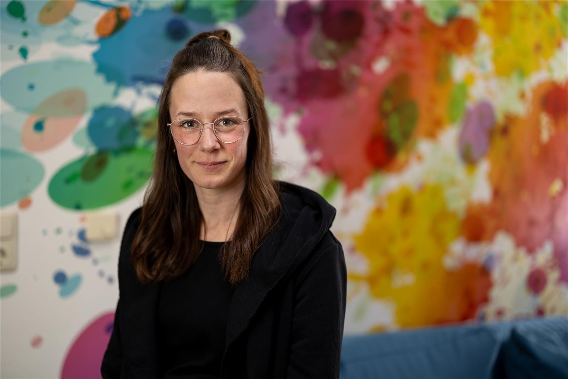 Junge Sozialarbeiterin vor einer bunten Grafitti-Wand