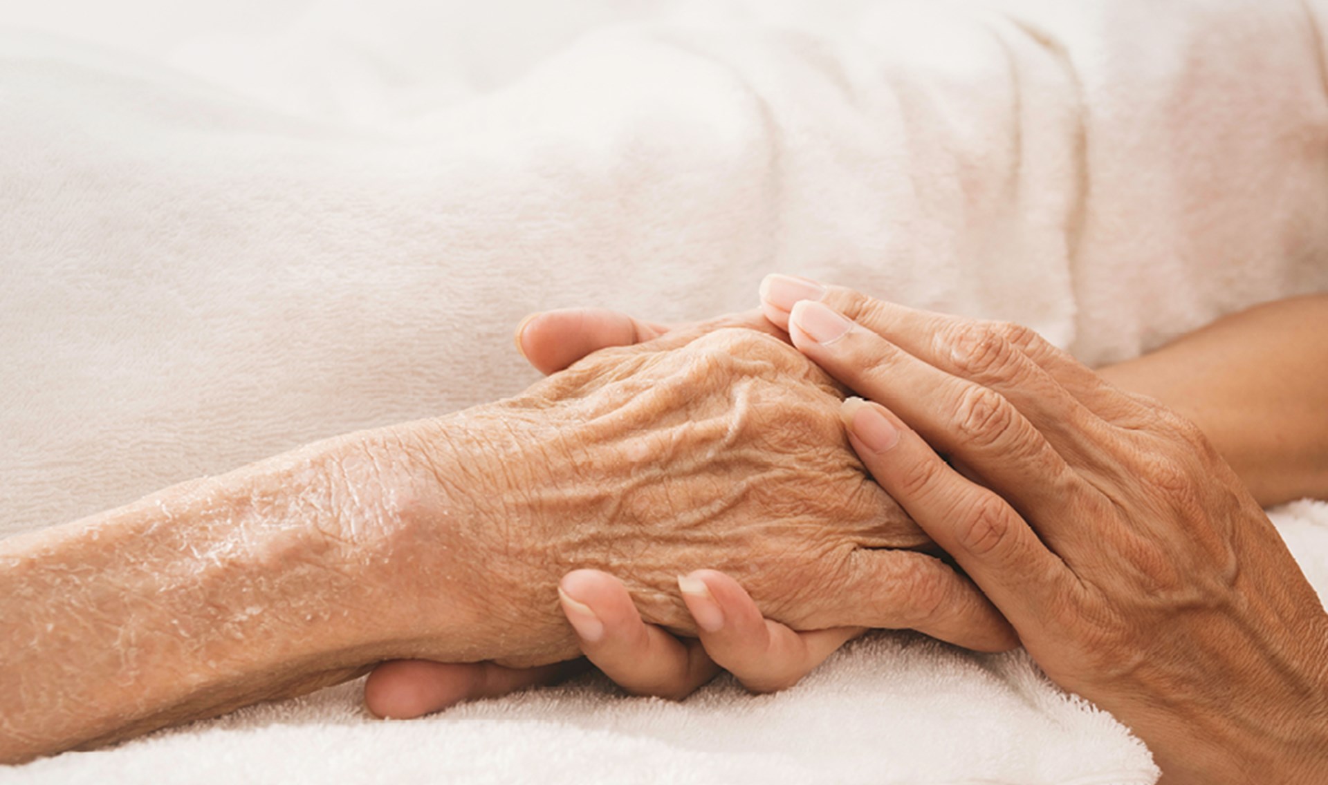 Eine Person hält mit beiden Händen die Hand einer anderen Person