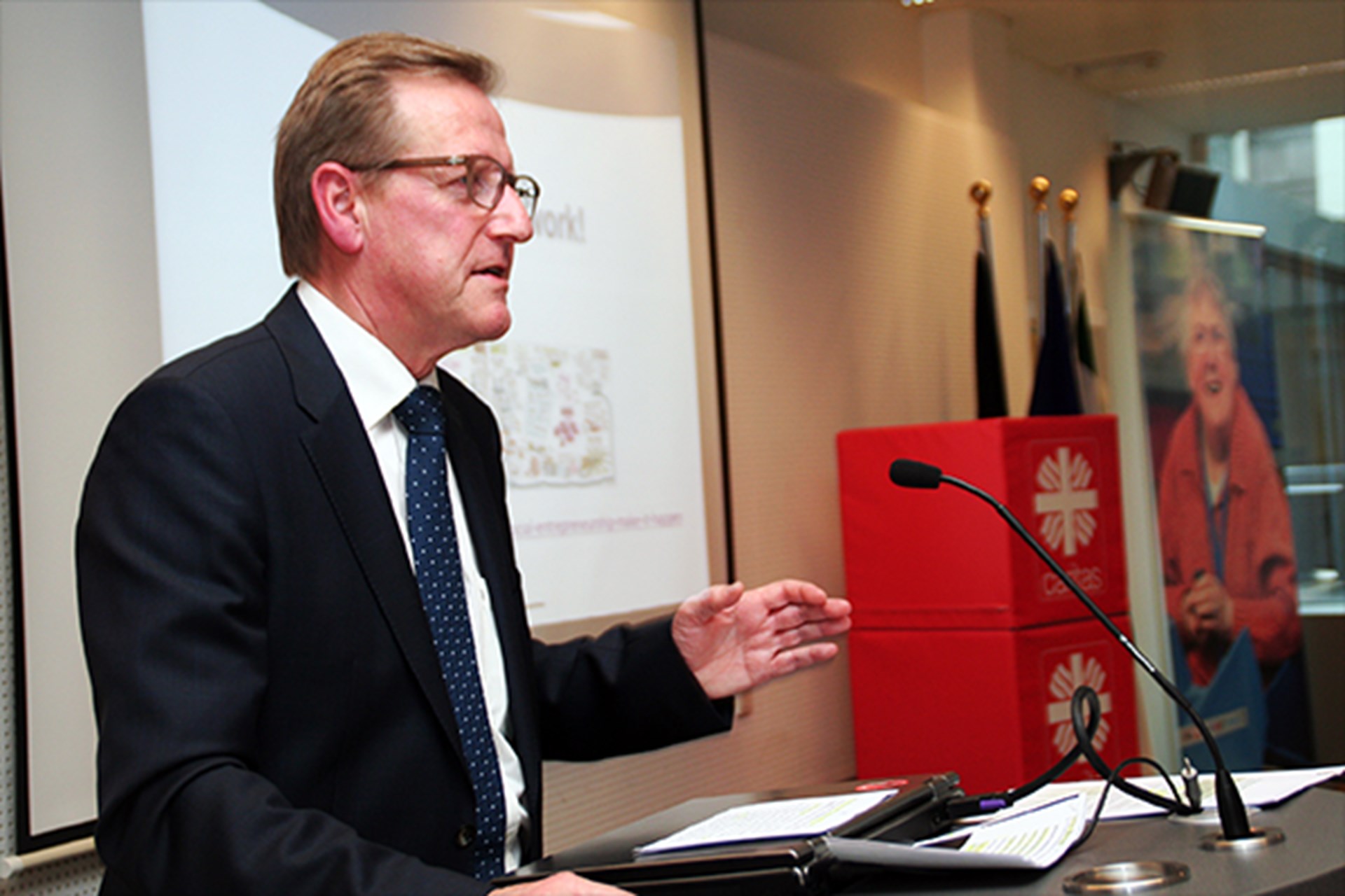 Ein Staatssekretär vom NRW-Ministerium für Arbeit, Integration und Soziales steht bei dem Europaforum der Caritas in NRW an einem Pult und hält eine Rede