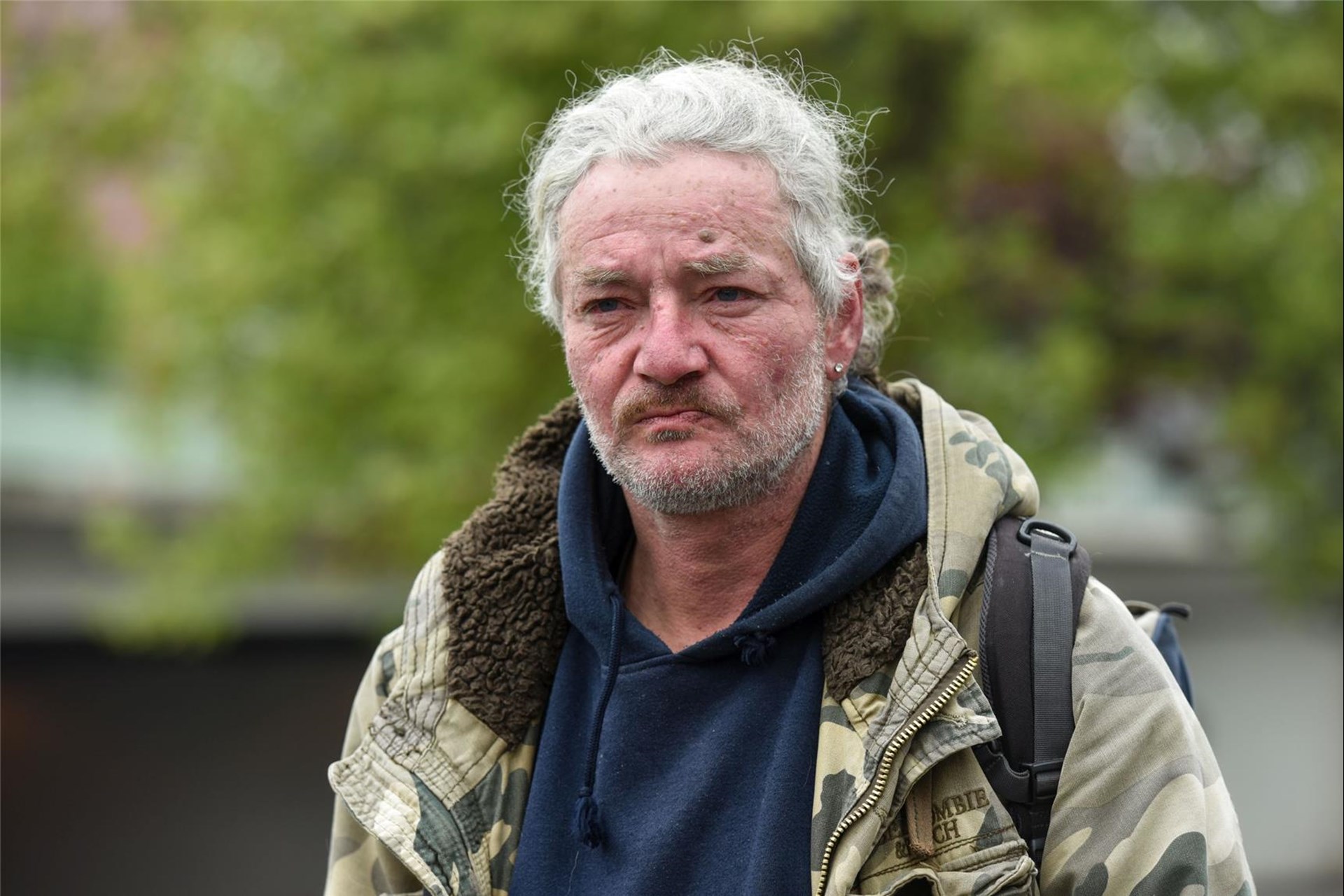  Mann mit weißen hinten zusammen gebundenen Haaren und Stoppelbart
