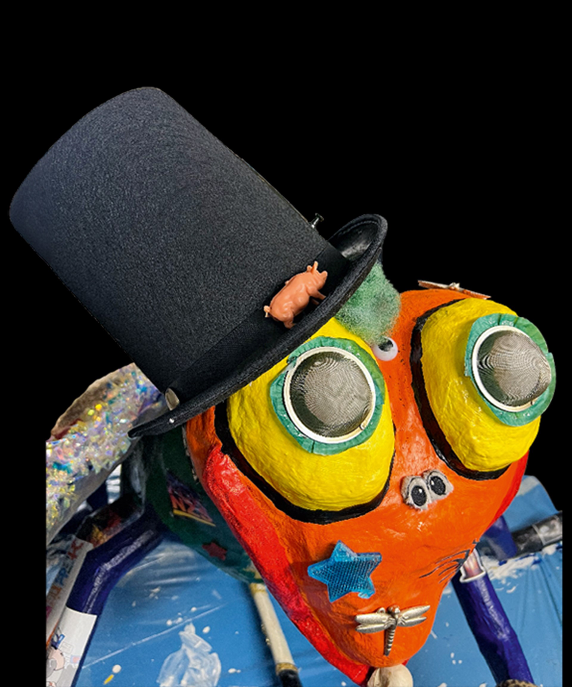 Ein bunt bemaltes Kunstwerk aus Pappmaché, dem ein schwarzer Zylinder aufgesetzt wurde
