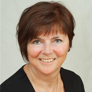 Lächelnde Frau mit braunen Haaren, die ein schwarzes Oberteil trägt