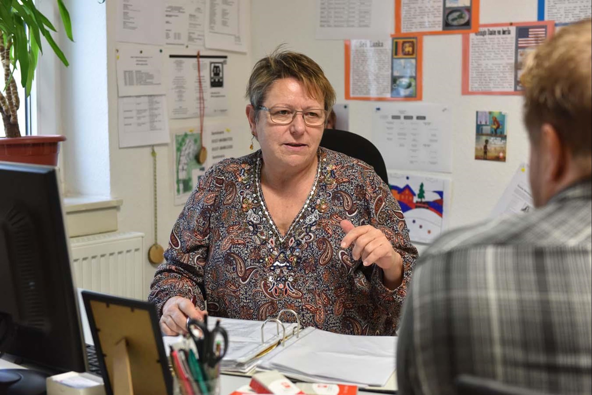 Eine Quartiersarbeiterin berät in ihrem Büro einen Mann