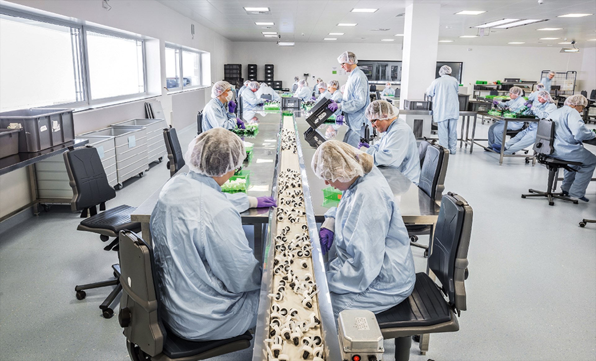 Eine größere Gruppe von Frauen und Männern in Schutzkleidung arbeiten in der CBW in Eschweiler an einem Fließband