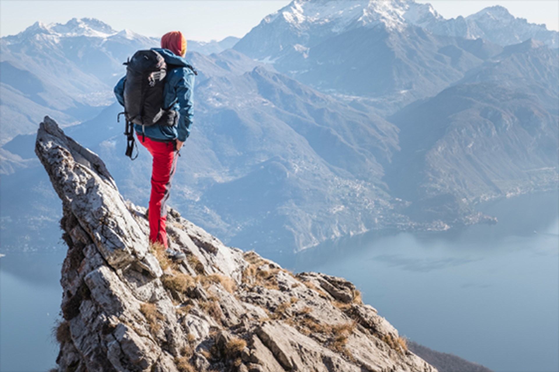 Ein Wanderer der auf der Spitze eines Berges steht und in die Landschaft blickt