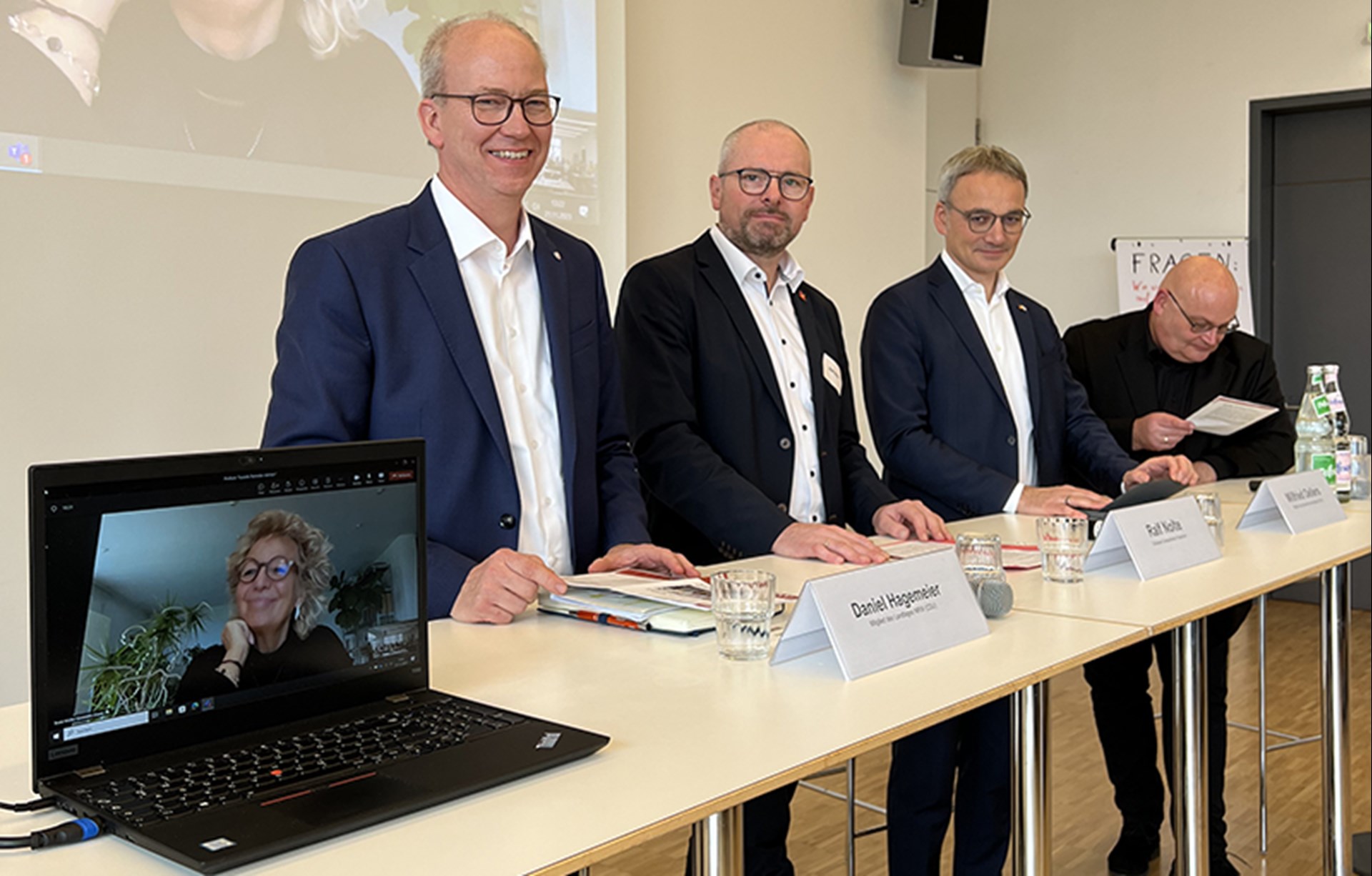Die Referierenden bei der Fachtagung 'Soziale Betriebe stärken – Teilhabe nachhaltig gestalten' der Caritas in NRW in Düsseldorf, die an einem langen Stehtisch stehen. Eine Referentin ist per Video zugeschaltet.