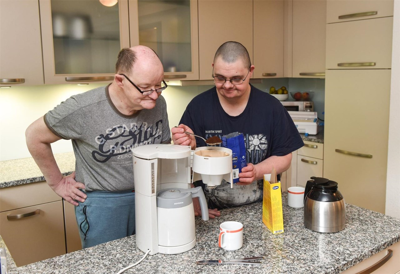 Zwei Männer mit Behinderung bereiten gemeinsam Kaffee zu