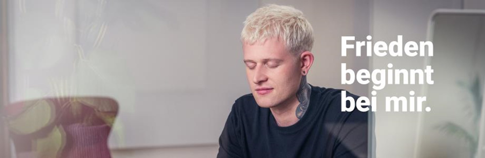 Ein junger Mann mit kurzen blondierten Haaren mit der Aufschrift "Friede beginnt bei mir."